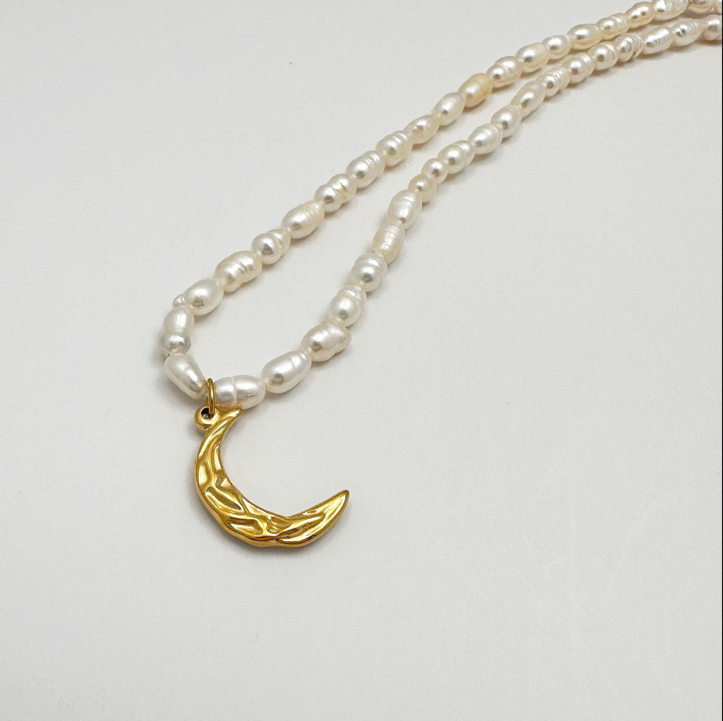 Time-honored freshwater pearl necklace with a unique 18k gold plated crescent moon charm.