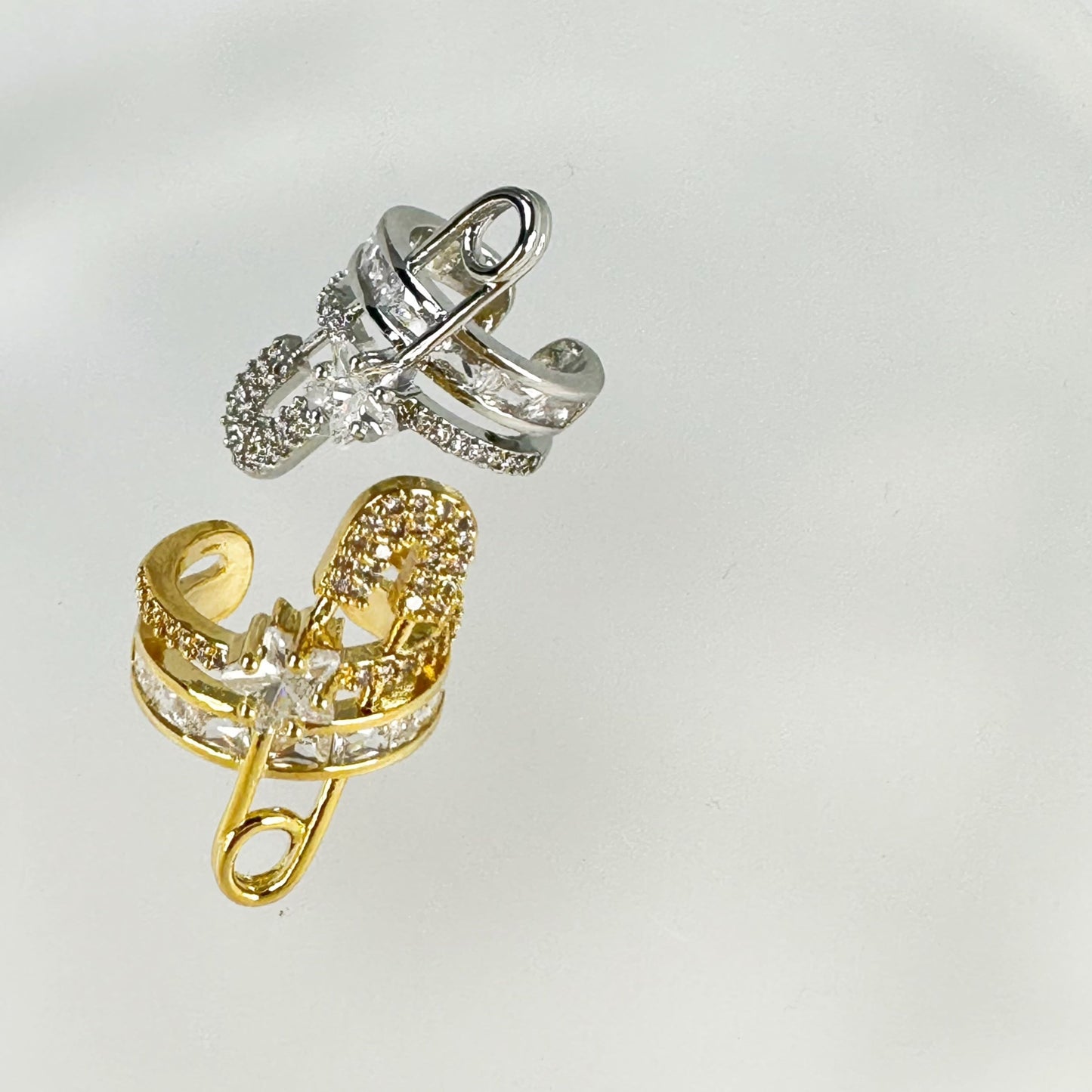 Gold plated ear cuff in a unique paper clip design, embellished with sparkling cubic zirconia, isolated on a white background