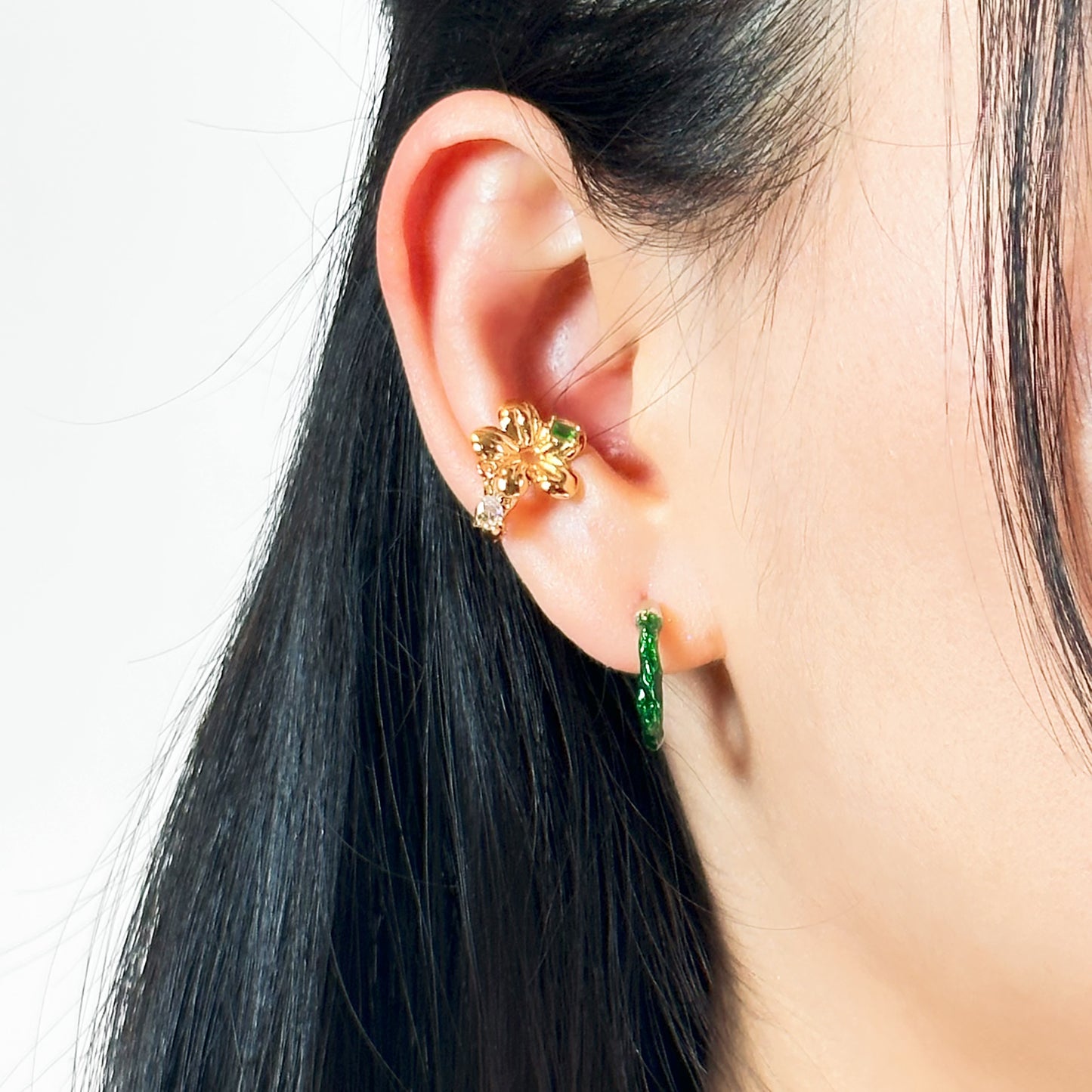 Elegant ear cuff with 18k gold plating, showcasing a bright green gemstone and delicate gemstone drop detail.