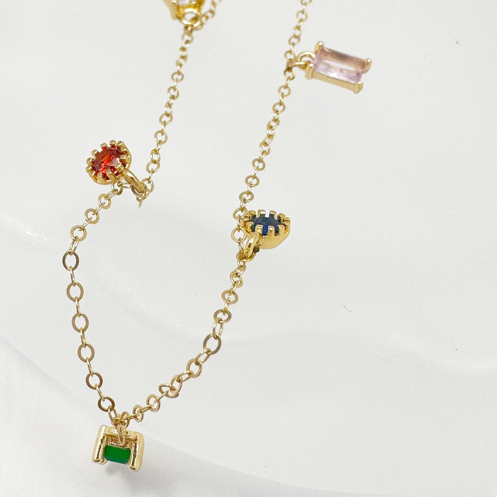 Gold-filled chain necklace adorned with multicolored zircon gemstones in green, red, blue, and purple.