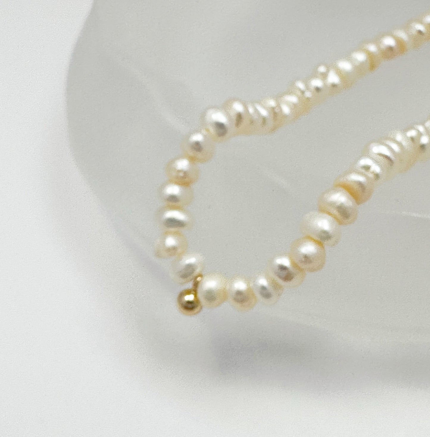 Timeless natural pearl necklace with a distinctive gold-filled ball in the center