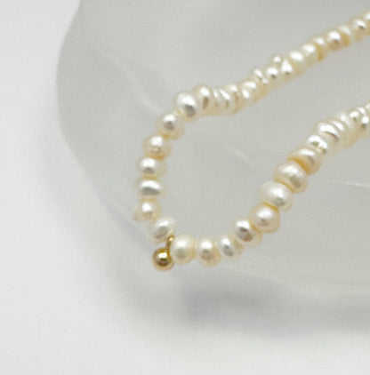 Timeless natural pearl necklace with a distinctive gold-filled ball in the center