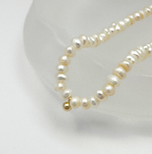 Timeless natural pearl necklace with a distinctive gold-filled ball in the center