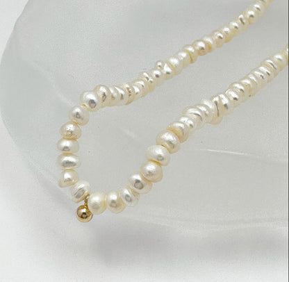 Timeless natural pearl necklace with a distinctive gold-filled ball in the center