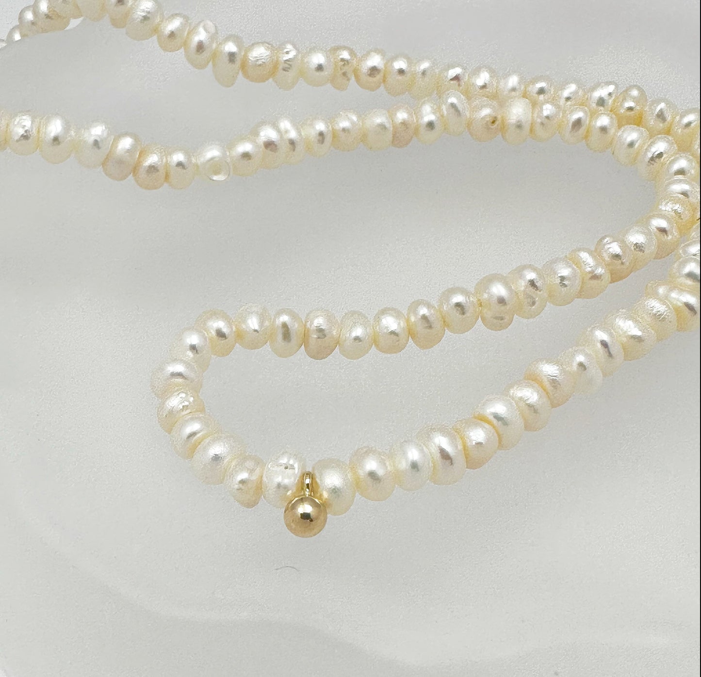 Timeless natural pearl necklace with a distinctive gold-filled ball in the center