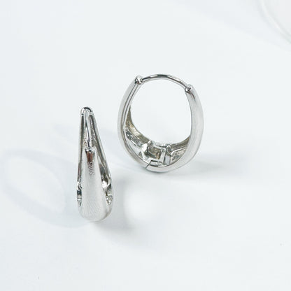 Delta Hoop Earrings crafted from S925 silver, featuring a smooth, polished surface with a distinct, curvaceous design visible from multiple angles