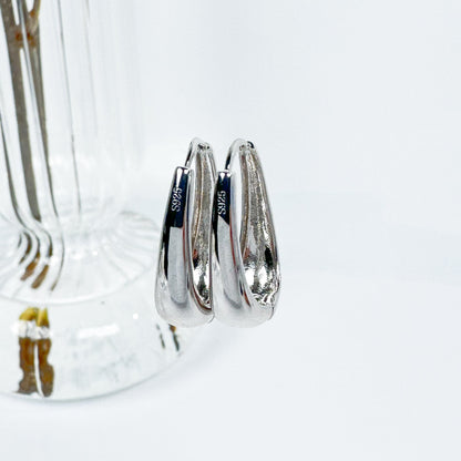 Delta Hoop Earrings crafted from S925 silver, featuring a smooth, polished surface with a distinct, curvaceous design visible from multiple angles